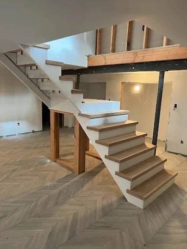 Open-riser staircase with white stringers and wood treads during a renovation