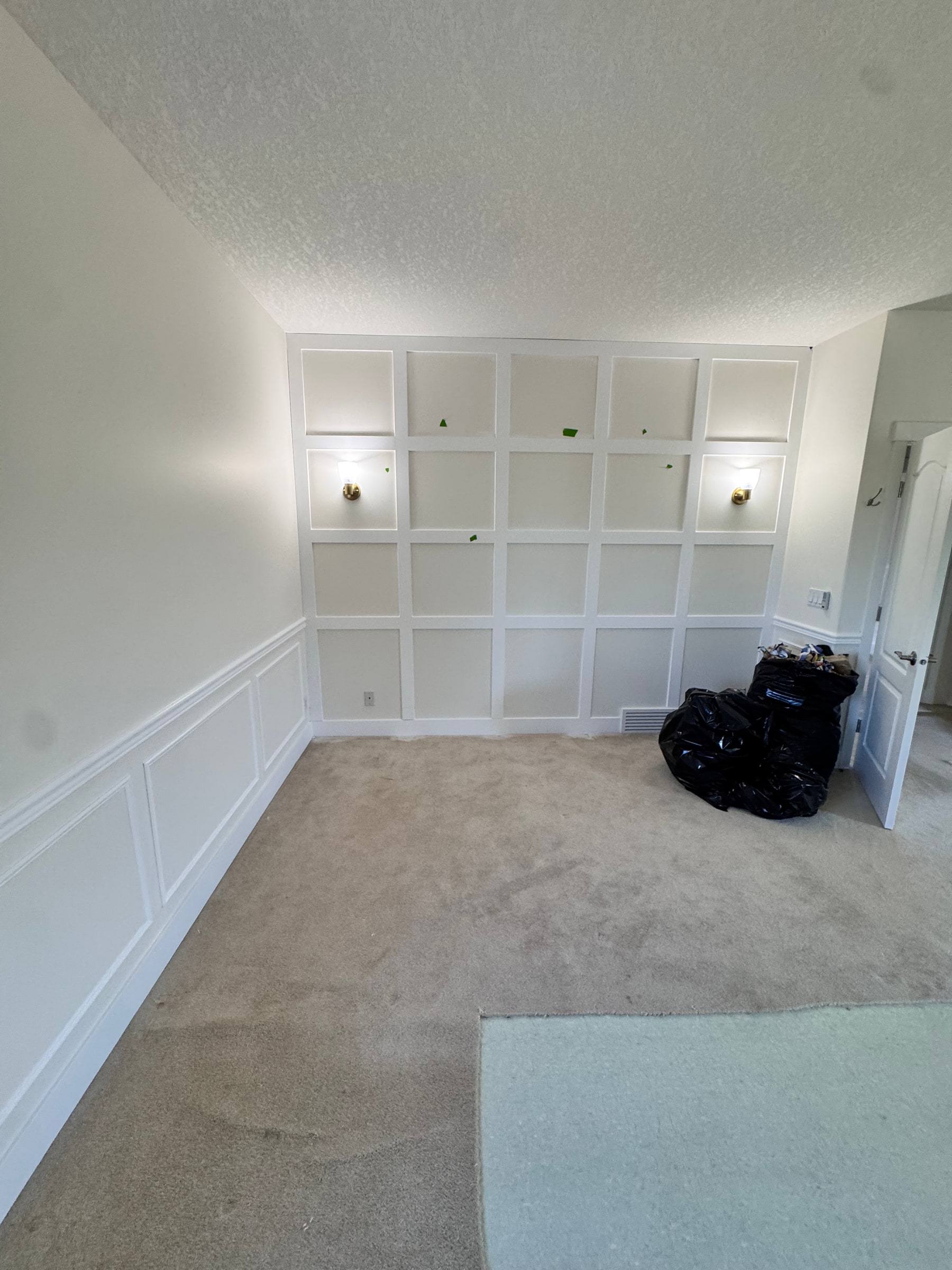 Room with a square grid feature wall above wainscoting that wraps around the side walls