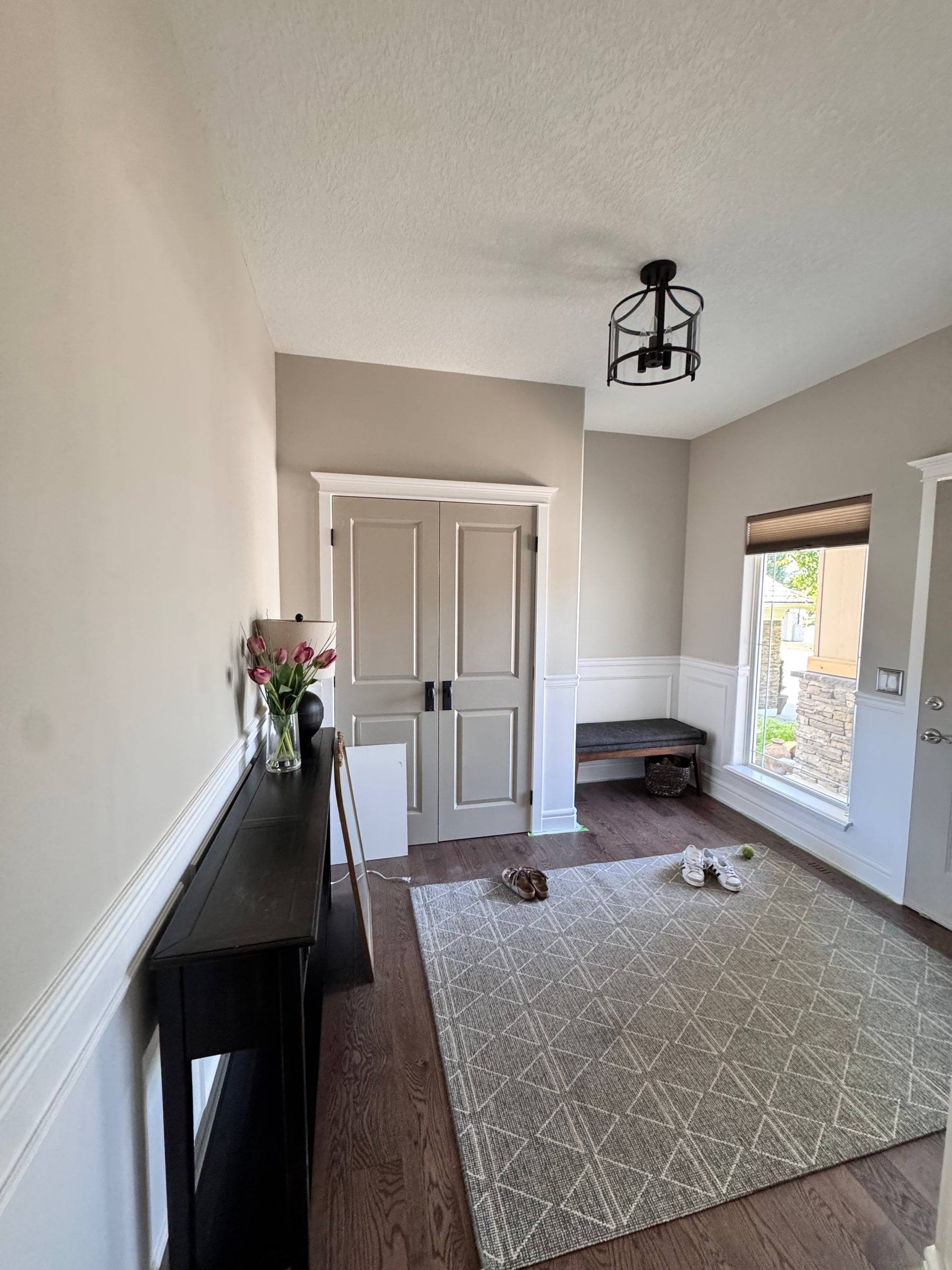 Front entry with chair rail wainscoting, a bench and white double closet doors